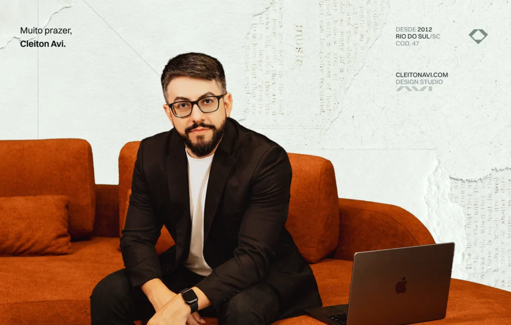 Fotografia profissional de Cleiton Avi sentado no sofá com seu MacBook