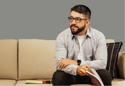 Cleiton Avi sentado no sofá com um livro nas mãos